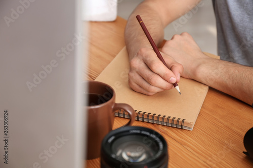 Photographer writing in notebook at table