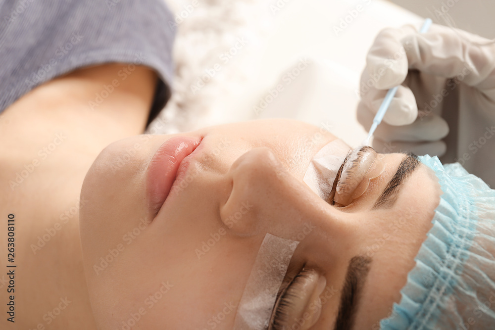 Naklejka premium Young woman undergoing procedure of eyelashes lamination in beauty salon