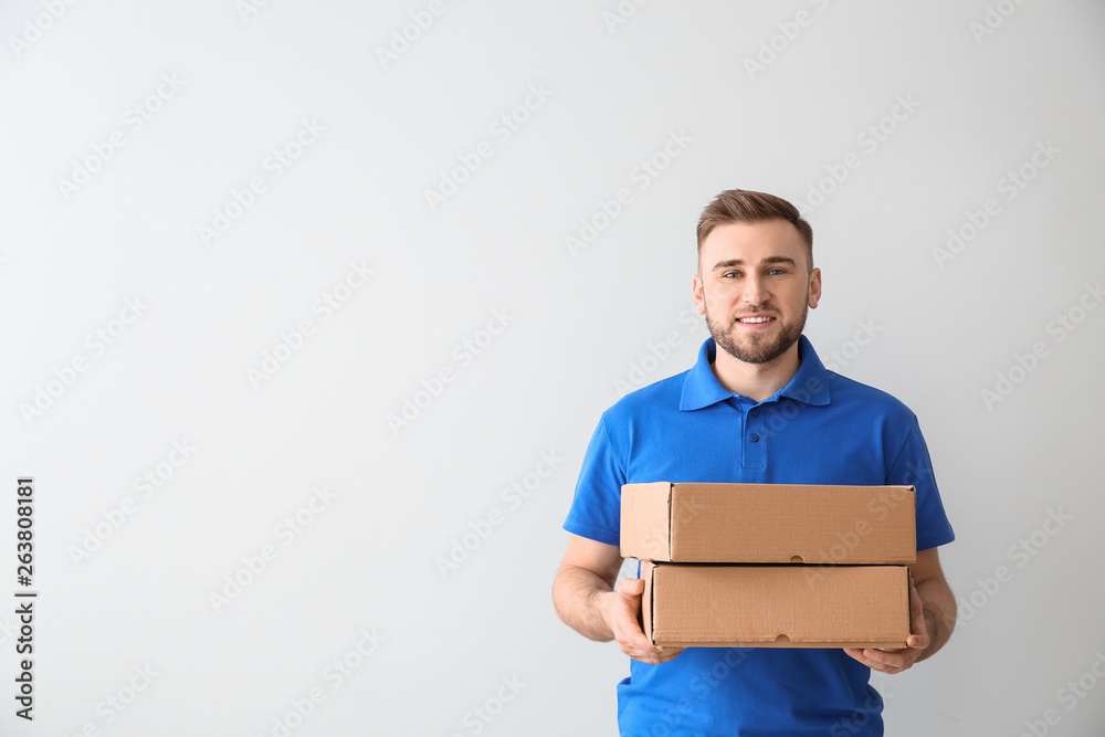 Handsome delivery man with boxes on light background Handsome delivery man with boxes on light background