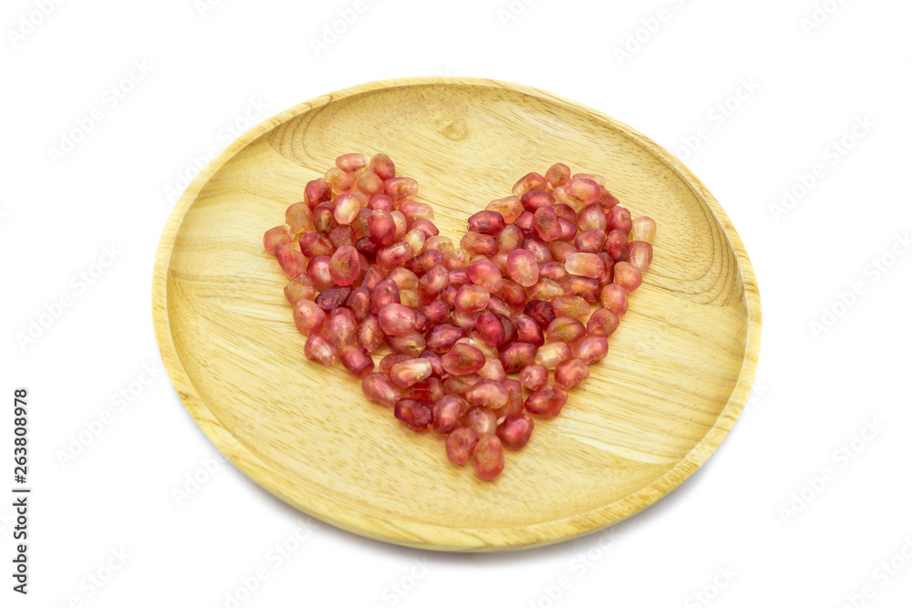 Fresh pomegranate heart shape on wooden plate isolated on white background Fresh pomegranate heart shape on wooden plate isolated on white background