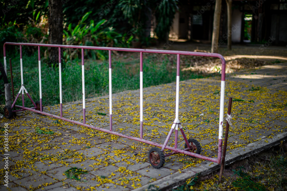 Fototapeta premium The background of the steel fence is red in color and has a small rubber wheel, can easily be used to block the car in-out area in the garden.