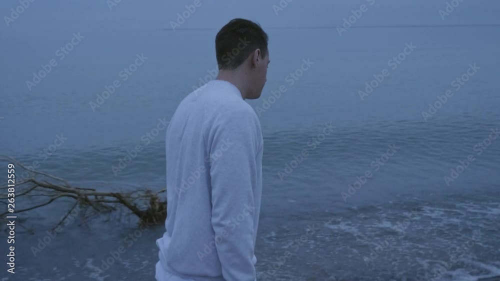 Caucasian man taking a stroll next to a cold foggy lake Caucasian man taking a stroll next to a cold foggy lake