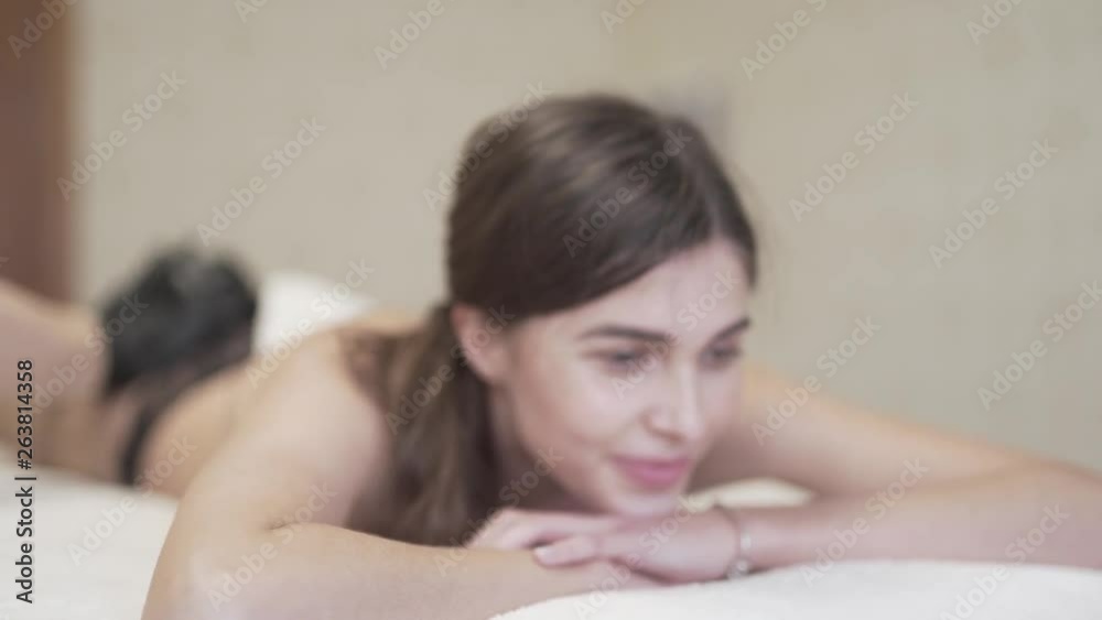 The female client receives a high-quality massage as the massage table and the client herself shake from it. The masseuse wears a special uniform and gloves. The young lady smiles. Blurred Background The female client receives a high-quality massage as the massage table and the client herself shake from it. The masseuse wears a special uniform and gloves. The young lady smiles. Blurred Background