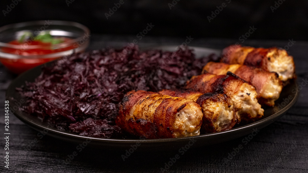 Fried homemade grilled sausages or chevapchichi with stewed sauerkraut and tomato sauce on a wooden rustic background
