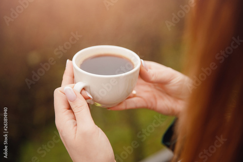 Closeup cup of coffee in hands of beautiful young woman