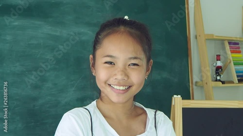 Young asian schoolgirl standing and smiling in classroom