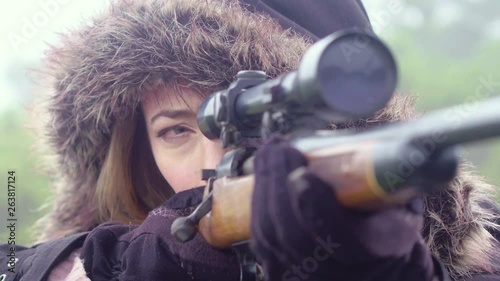 Close up of a woman holding still while aiming a rifle, 23.98 fps. photo