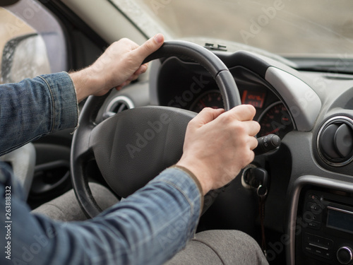 Male hands on steering wheel, inside cab, close up. Man driving a car.