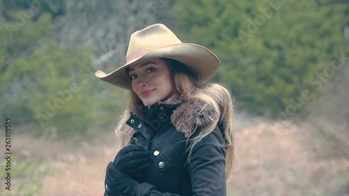 A woman wearing a cowboy hat and rugged up for winter looks flirtatious with her eyes, 29.97 fps.