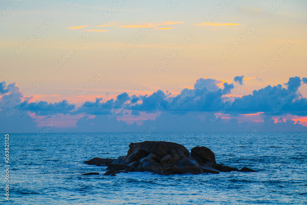 Fototapeta premium Rock in the sea waves at sunset beautiful, sea wave impact the stone on beach in the sunset time