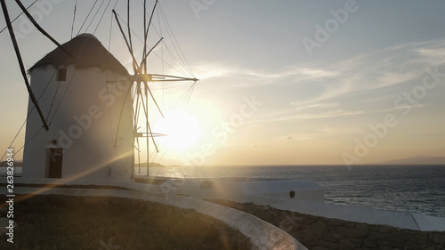 sunset shot of the windmills on mykonos greece with lens flare