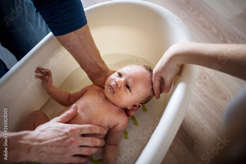 Papier peint Unrecognizable parents giving a newborn baby a bath at home.