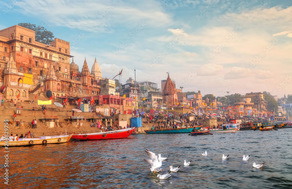 Varanasi Ganges river ghat with ancient city architecture with view of migratory birds on river Ganga at sunset.