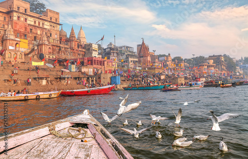 aranasi Ganges river ghat with ancient architecture buildings as viewed from a boat with migratory birds on river Ganga. photo