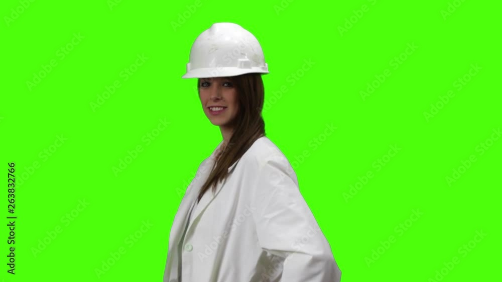 Young Brown Blonde Woman With White Doctor Lab Coat And Hard Hat Looks Smiling At Camera Then Faces Camera And Crosses Her Arms Young Brown Blonde Woman With White Doctor Lab Coat And Hard Hat Looks Smiling At Camera Then Faces Camera And Crosses Her Arms