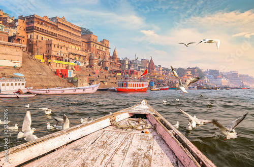 Historic Varanasi city architecture with Ganges river ghat at sunset with view of migratory birds  photo