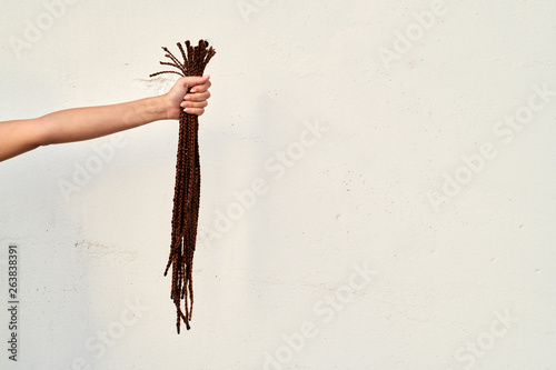 Woman's arm with cut hair over wall.