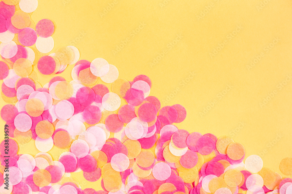 Orange, pink and white confetti on orange background. Flat lay style. Top view. Copyspace for text.