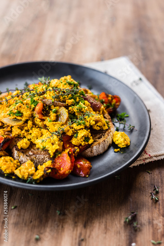 vegan tofu scramble on sourdough toast, on wooden rustic tableto photo