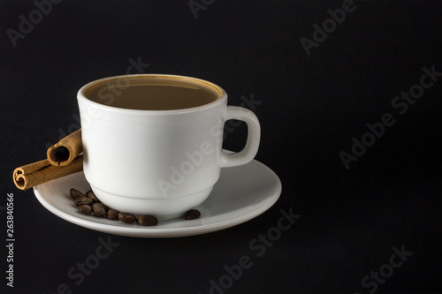 White cup of hot coffee and Cinnamon sticks isolated on black background.