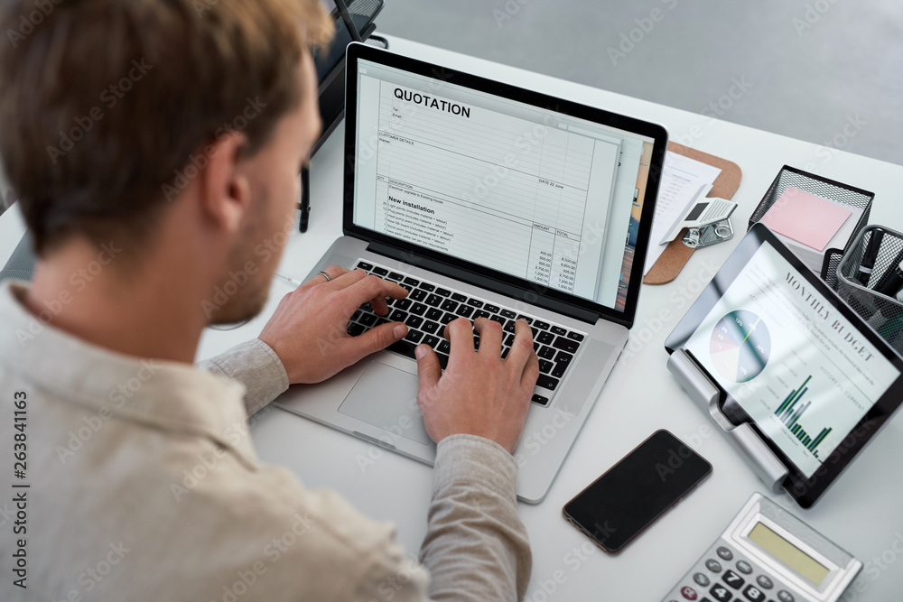 Over shoulder of businessman working on laptop in office Over shoulder of businessman working on laptop in office