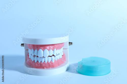 Typodont teeth and floss on color background, space for text. Dentist consultation