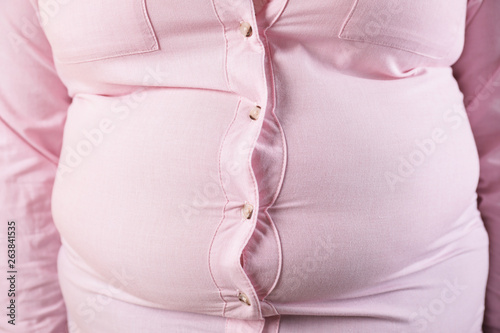 Overweight woman in tight shirt, closeup. Obesity and weight loss