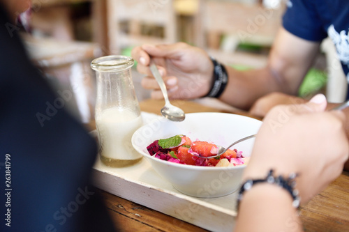 Couple sharing a healthy breakfast bowl of tropical fruit, granola and coconut smoothie photo