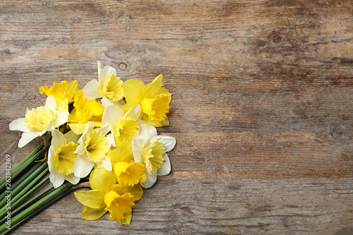 Bouquet of daffodils on wooden background, top view with space for text. Fresh spring flowers