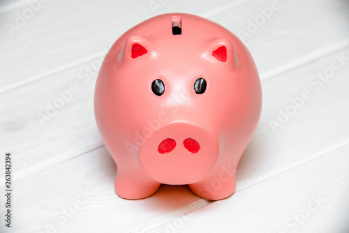Piggy Bank stands on a white wooden background 