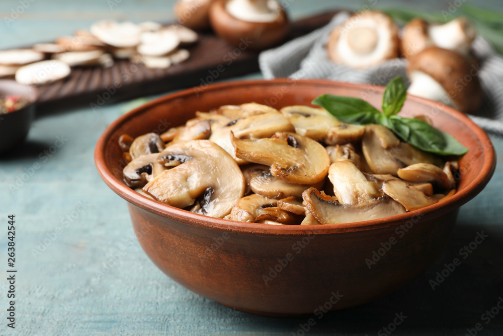 Delicious cooked mushrooms with basil in bowl on table Delicious cooked mushrooms with basil in bowl on table