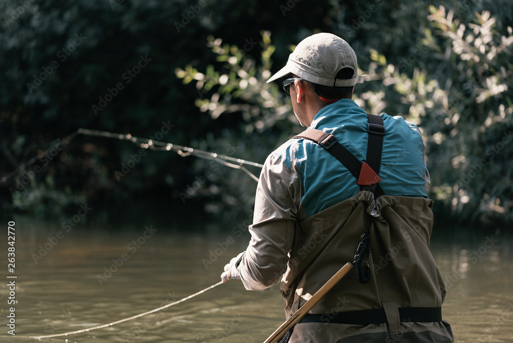 Unrecognizable fly fisherman using flyfishing rod Unrecognizable fly fisherman using flyfishing rod