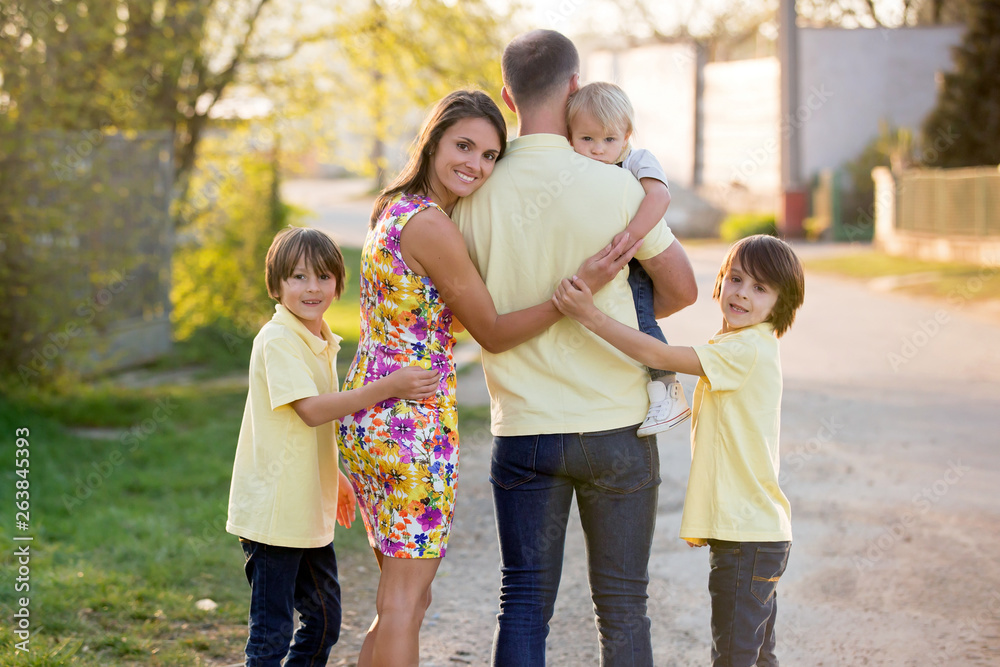 Beautiful family, mother, father and three kids, boys, having familly outdoors portrait taken on a sunny spring evening, beautiful blooming garden, sunset time Beautiful family, mother, father and three kids, boys, having familly outdoors portrait taken on a sunny spring evening, beautiful blooming garden, sunset time