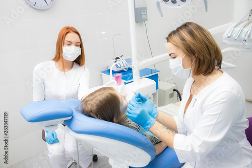 a female dentist and her assistant treat a little girl s teeth