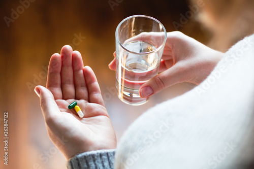young woman taking pills with water