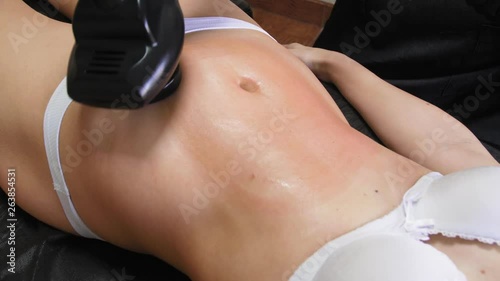 The thin woman is receiving the vacuum massage her belly with LPG tool while lying in the spa salon. Cosmetology procedure of a beautiful figure of the young woman. 4k