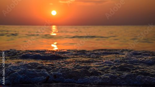 sunrise at the shore of the sea and ocean, seen from the sand level, with the glowing wave of water, and pleasant bokeh photo