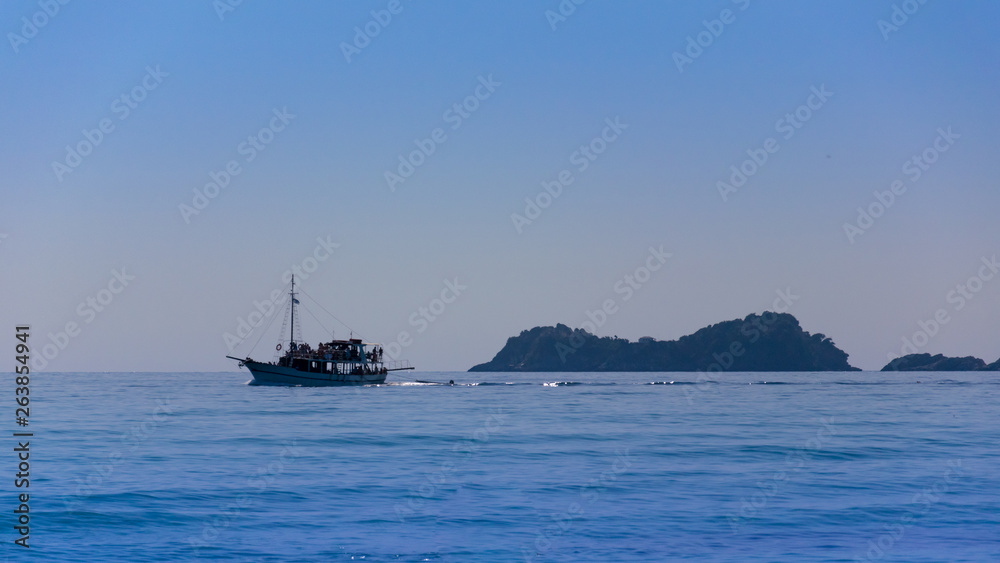 sailing vessel on the Mediterranean Sea, with blue water and rocks seen from afar