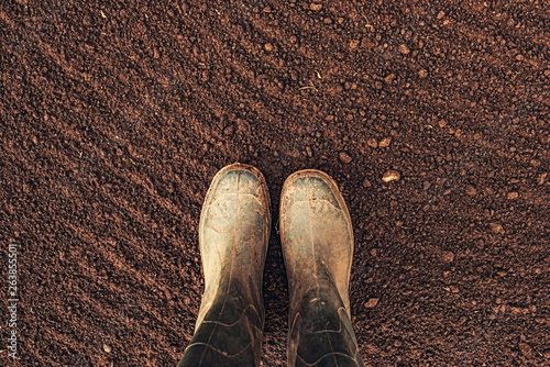 Top view of farmer rubber boots on ploughed arable land photo