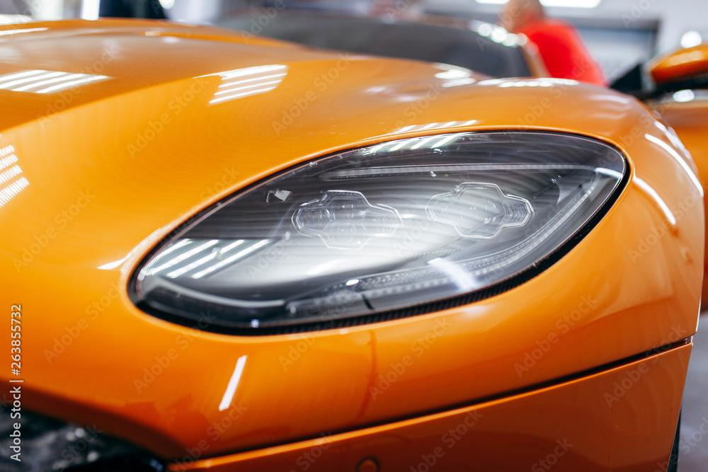 Orange modern car closeup on black background