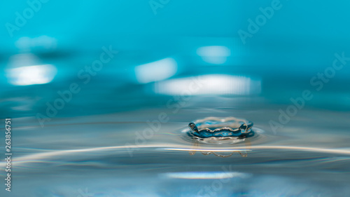 water splash in colorful background with a drop of water flying from above
