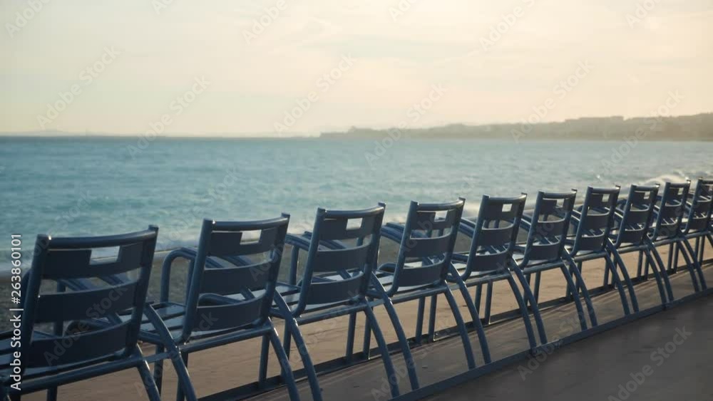 A row of empty beach chairs for tourists and hotel resort guests to sit at and enjoy a sunny beach vacation in Nice, France.