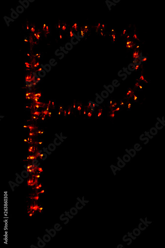 The letter "P" of the English alphabet made of red electric garland on a dark background, blur, bokeh, isolated on black