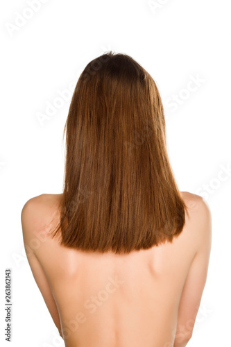 Back view of young nude woman with long hair on white background