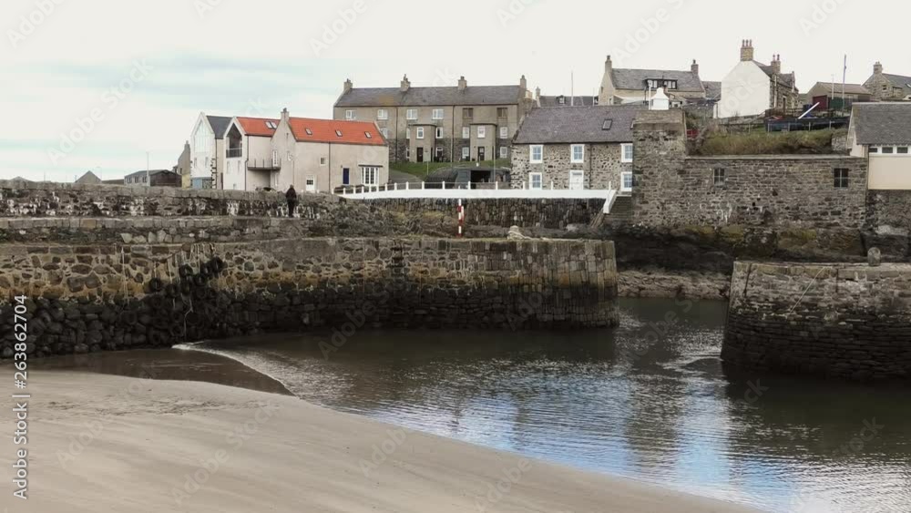 Portsoy Harbour lady walks along harbour wall Portsoy Harbour lady walks along harbour wall