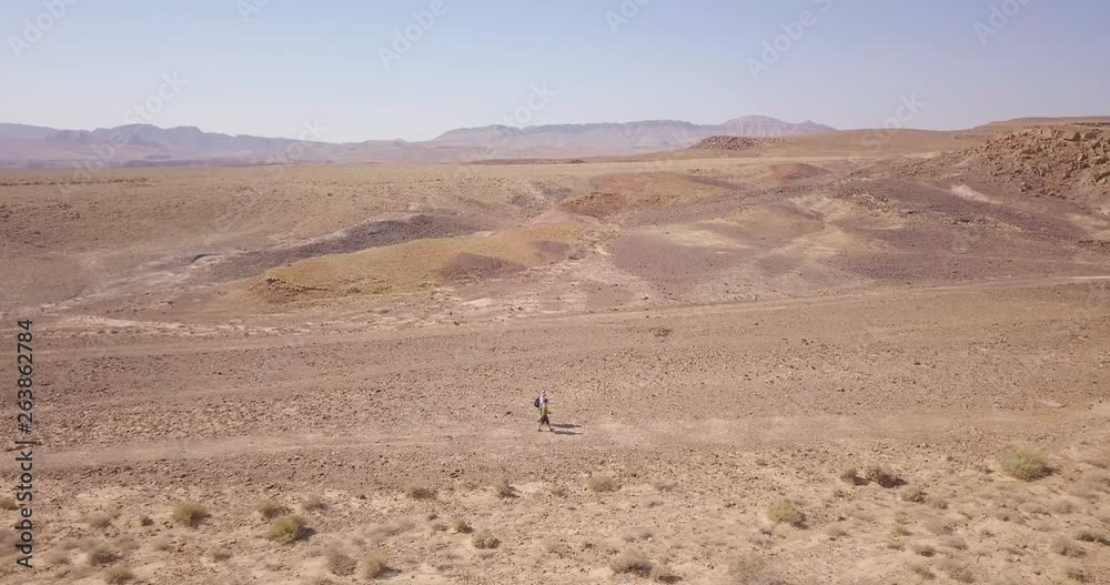Dolly aerial wide shot of hikers walking in the middle of the Negev Desert, Israel Dolly aerial wide shot of hikers walking in the middle of the Negev Desert, Israel