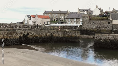 Portsoy Harbour lady walks along harbour wall photo