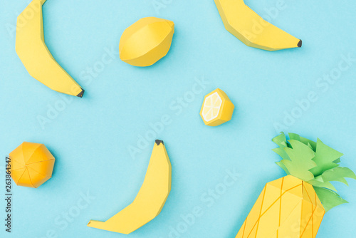 top view of handmade paper lemons, bananas and pineapple isolated on blue