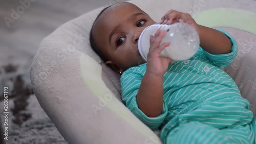 7 month old happy baby drinking milk from bottle right aligned