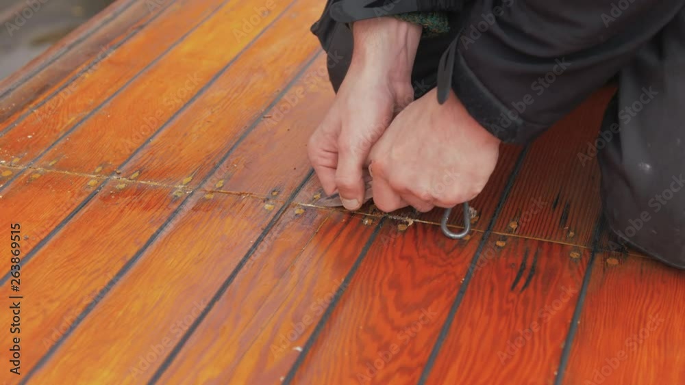 custom made wallpaper toronto digitalYoung man uses pocket knife to clean out old mastic of wooden boat roof planking close up